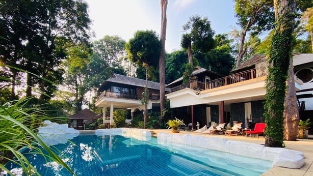 A pool area with a tiled pool, lounge chairs, and a covered seating area surrounded by trees. - Villa Hutan Datai (Langkawi)
