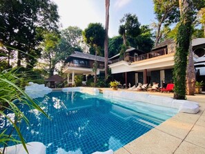A pool area with a tiled pool, lounge chairs, and a covered seating area surrounded by trees. - Villa Hutan Datai (Langkawi)