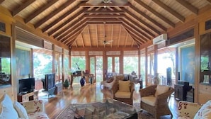 A spacious room with high wooden ceilings, a central glass coffee table, and comfortable seating. - Villa Hutan Datai (Langkawi)