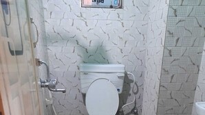Uma casa de banho pequena com sanita, chuveiro e lavatório.