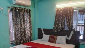 Quarto com cama, cortinas, ar condicionado e piso estampado.