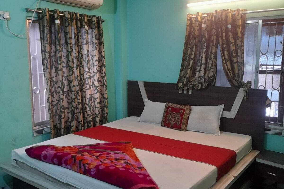 Quarto com cama, cortinas, ar condicionado e piso estampado.