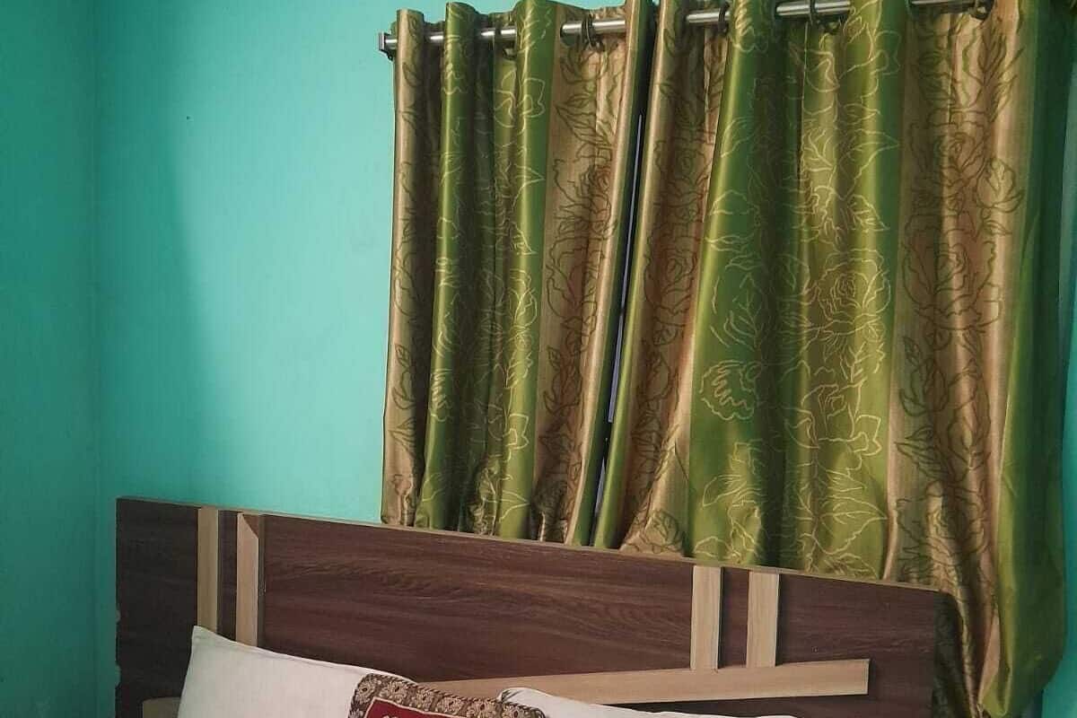 Uma cama com cabeceira de madeira, um travesseiro branco e um travesseiro vermelho com estampas florais.