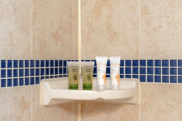 Un estante de baño con tres artículos de tocador: dos botellas de champú y una de acondicionador.