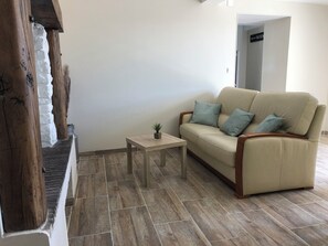 A living room with a beige sofa, a small wooden coffee table, and a potted plant.