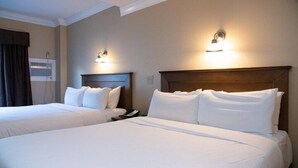 A hotel room with two beds, each with white linens and headboards, and wall-mounted light fixtures. - Comfy Room Along Banff Ave! Air-Conditioning (Banff)