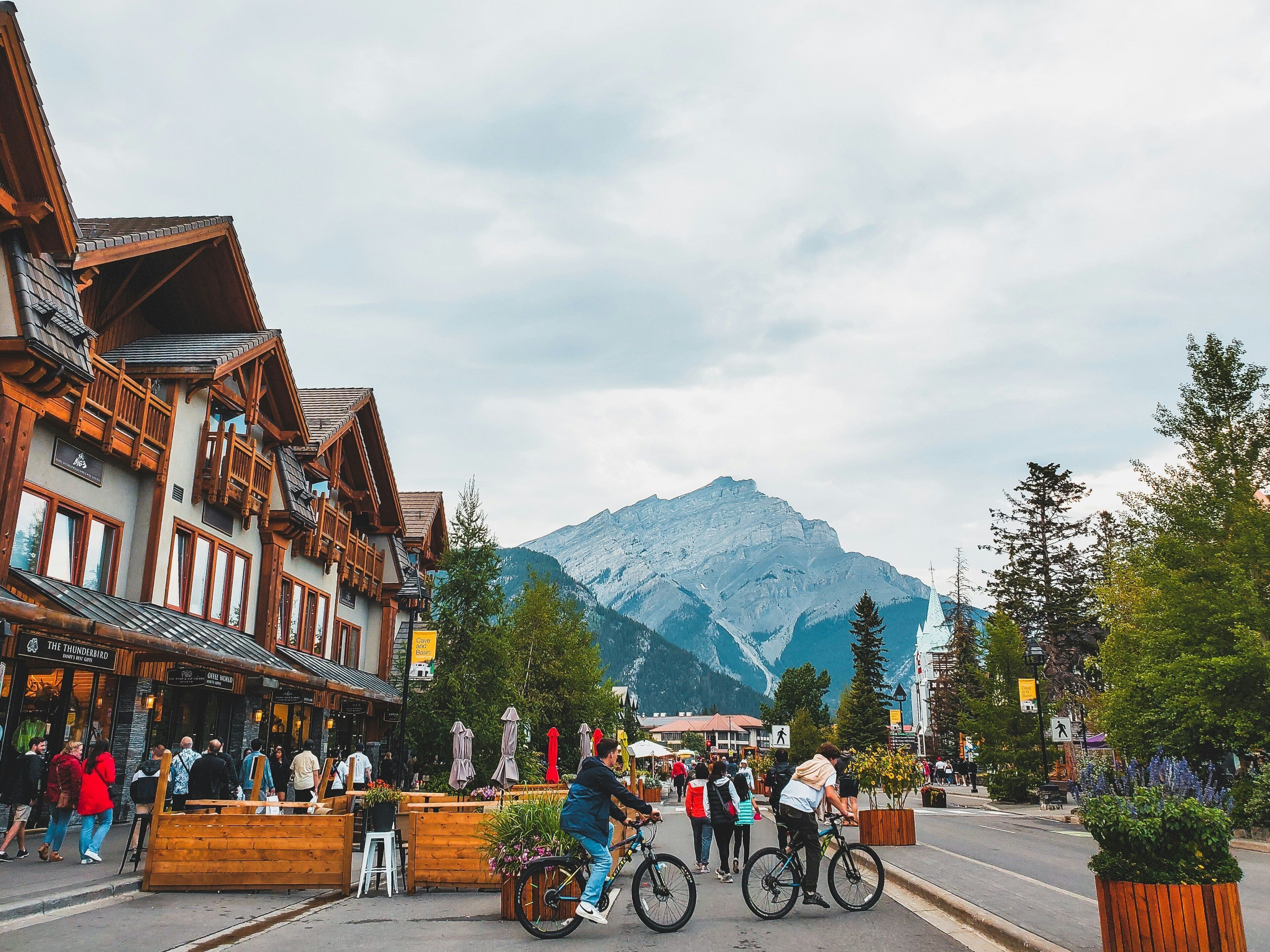 A mountain town with wooden buildings, a street with people, and a mountain in the background.