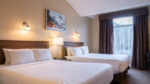 A hotel room with two beds, a painting on the wall, and a window with curtains.