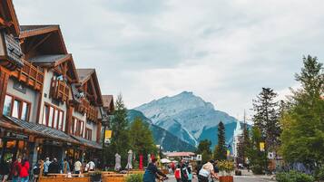 A mountain town with wooden buildings, a street with people, and a mountain in the background.