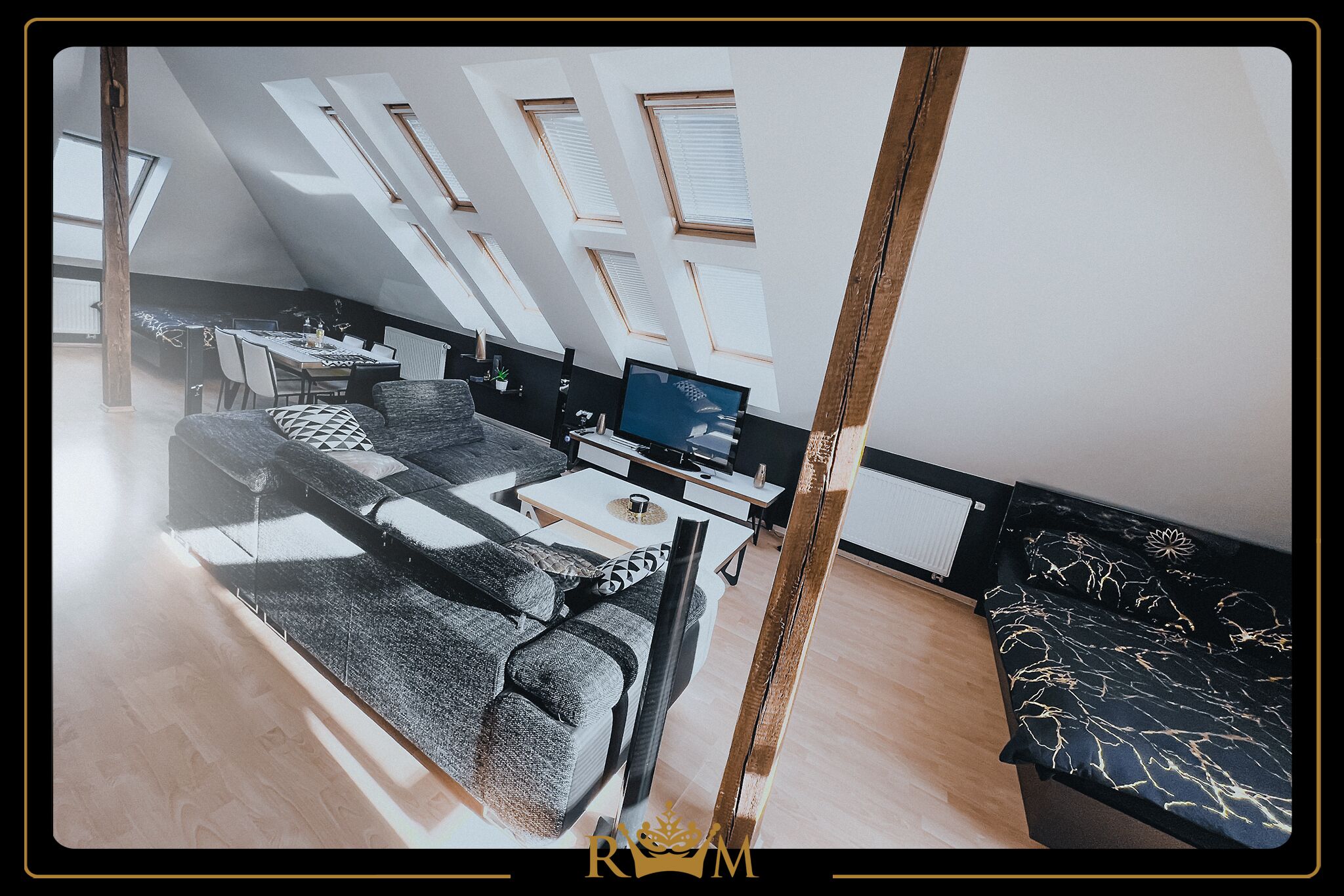 A modern loft bedroom with skylights, a sofa, a TV, and a dining area.