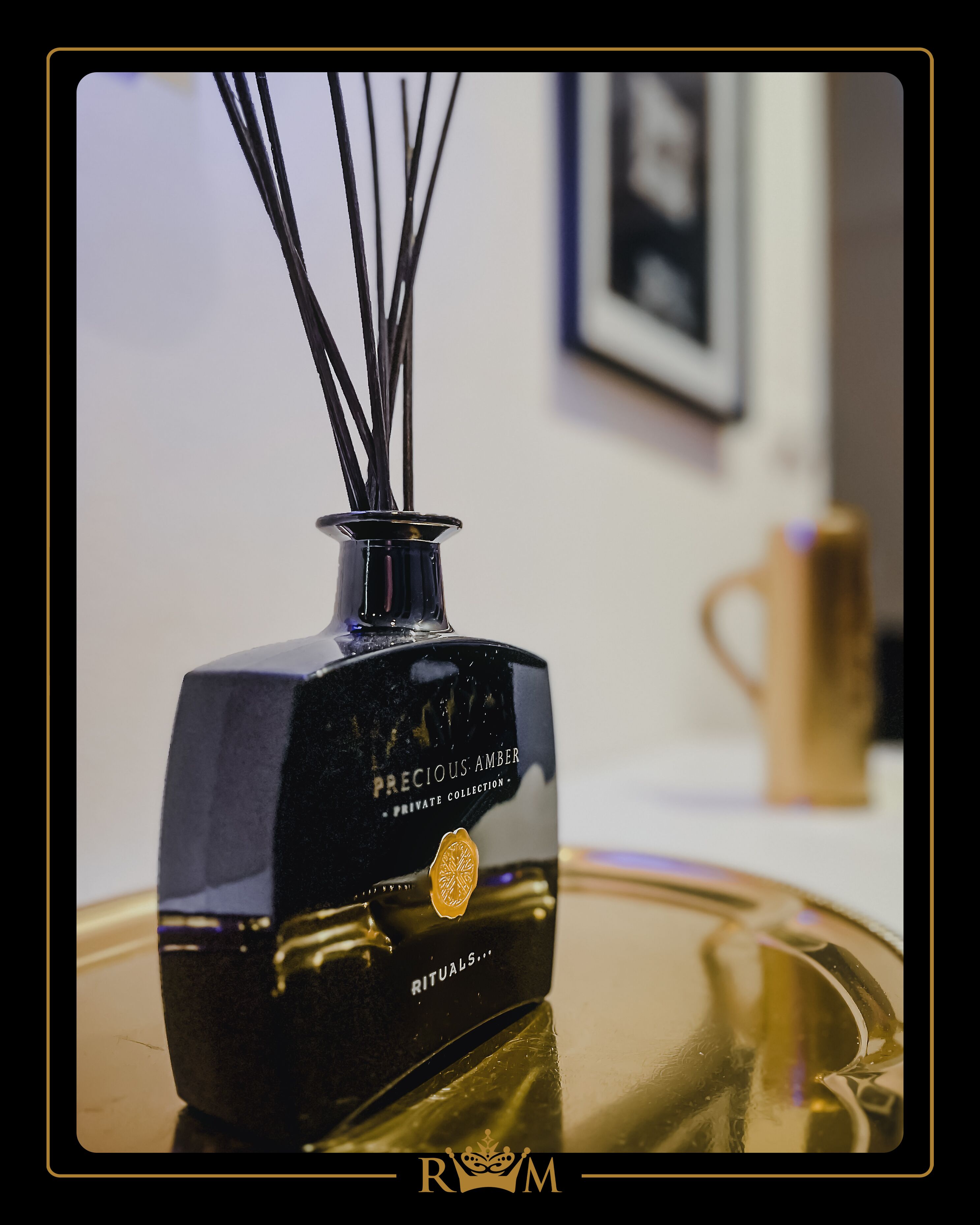 Una botella negra con un emblema dorado que dice "Precious Amber" sobre una superficie reflectante.