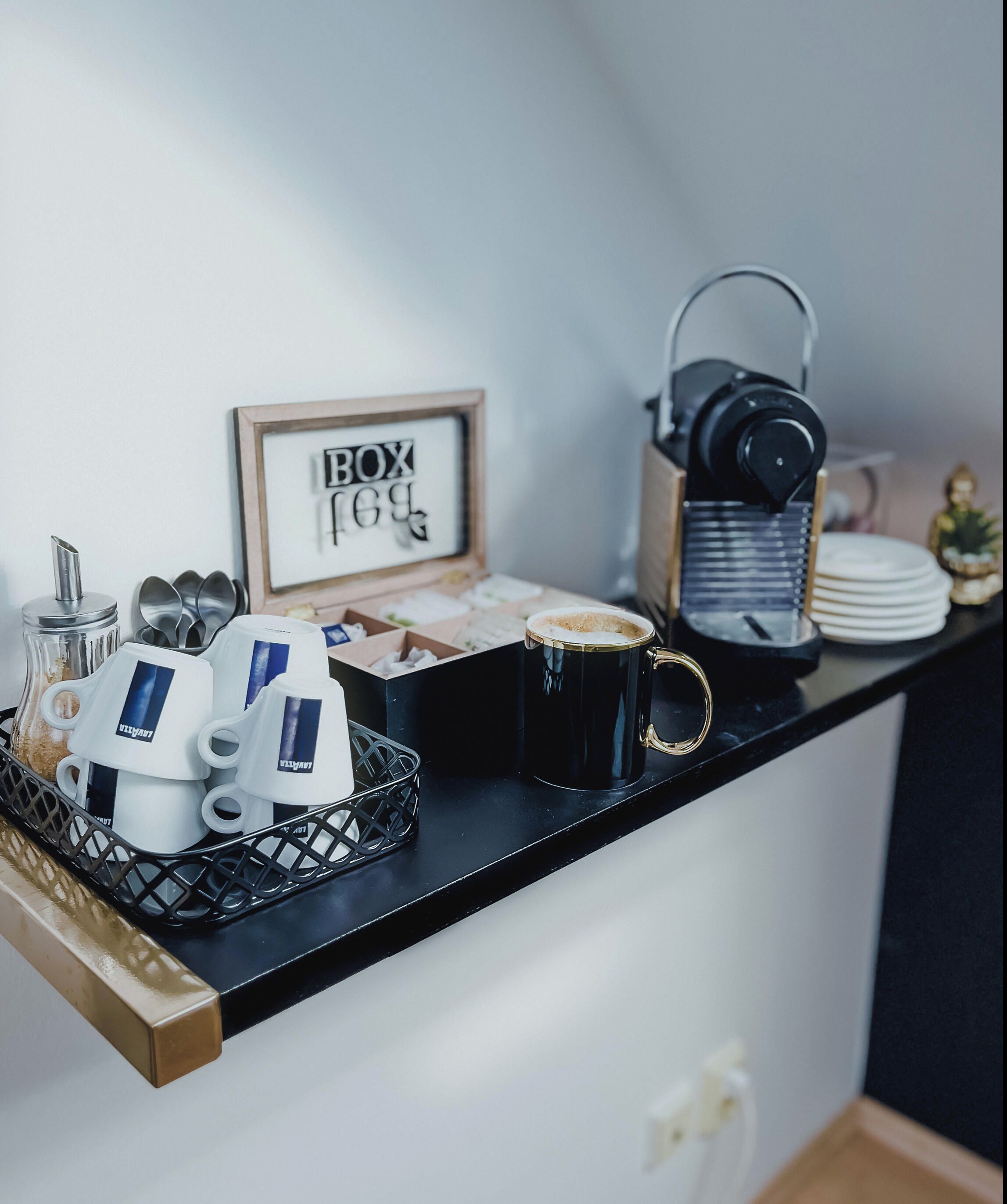 A coffee station with a coffee machine, cups, and a sign that reads 'BOX 169'.