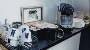 A coffee station with a coffee machine, cups, and a sign that reads 'BOX 169'.