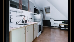 Een compacte keuken met witte kasten, een inbouwoven en een magnetron.