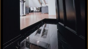 Een modern interieur met een deur met een zwart frame, een eethoek met een hoge plafond en dakramen.