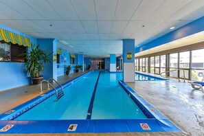 An indoor swimming pool with clear lane markings, safety signs, and potted plants. - XPLORIE ACTIVITIES & LINENS INCLUDED*! Direct Oceanfront 3BR/2BA condo in The Plaza. Indoor and Outdoor Pools and Tiki Bar. (Ocean City)