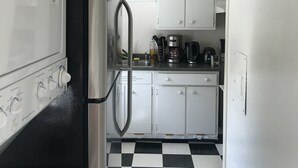 Une cuisine de taille réduite avec des meubles blancs, un réfrigérateur en acier inoxydable et un carrelage à motifs.