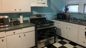 Eine Küche mit weißen Schränken, einem schwarz-weißen Schachbrettfußboden, einem Herd, einer Mikrowelle und einem Toaster.