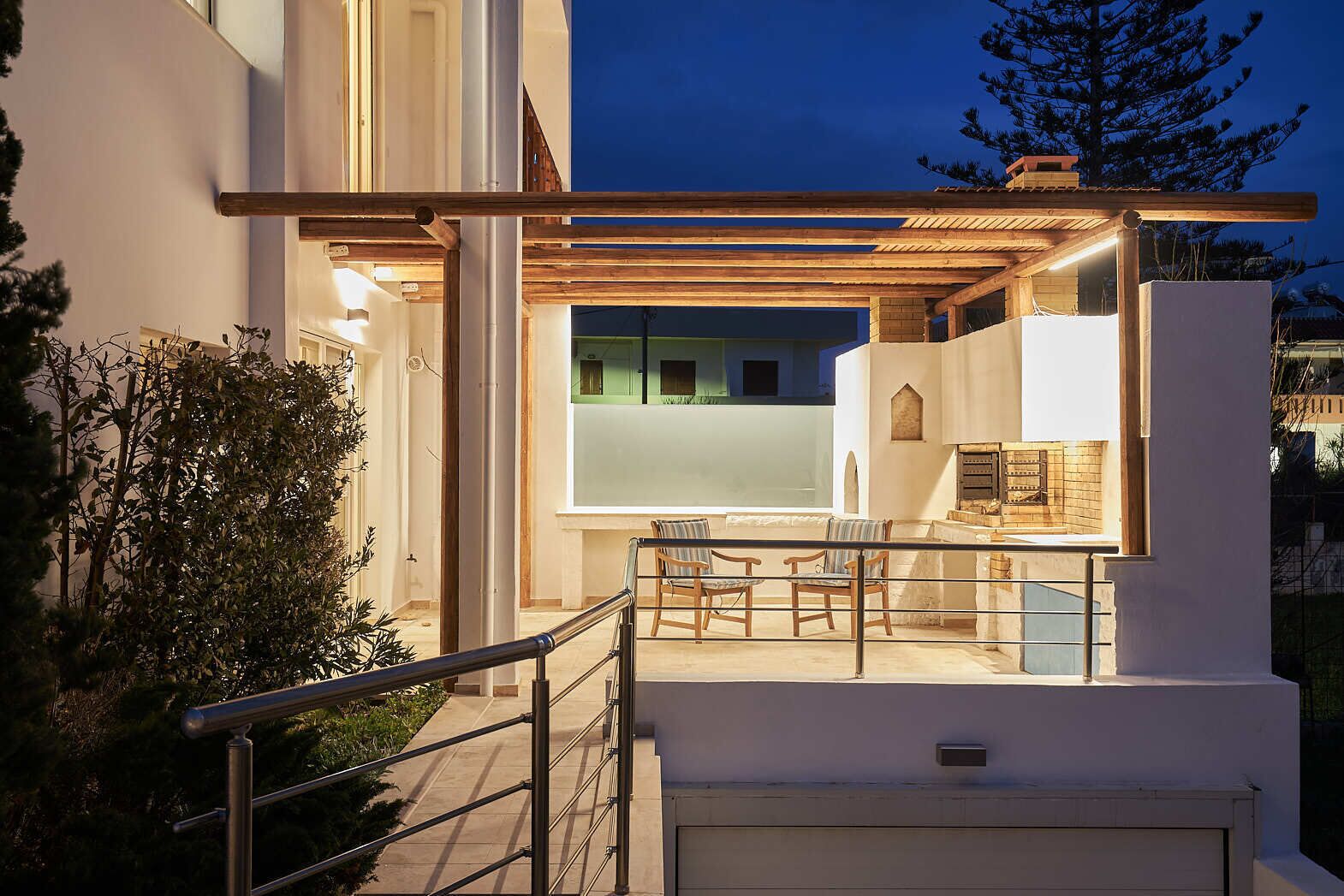 Une maison moderne dotée d’un espace extérieur aménagé et abrité, d’un garage apparent et d’un intérieur bien éclairé.