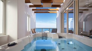Un jacuzzi con vista despejada al océano, vigas de madera en el techo y ventanas amplias.