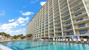 Ein Hotel mit mehreren Balkonen, einem Schwimmbad und blauem Himmel.