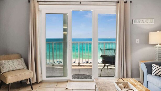 Ein Zimmer mit Blick auf den Strand, eine Couch, ein Sessel und eine Lampe.