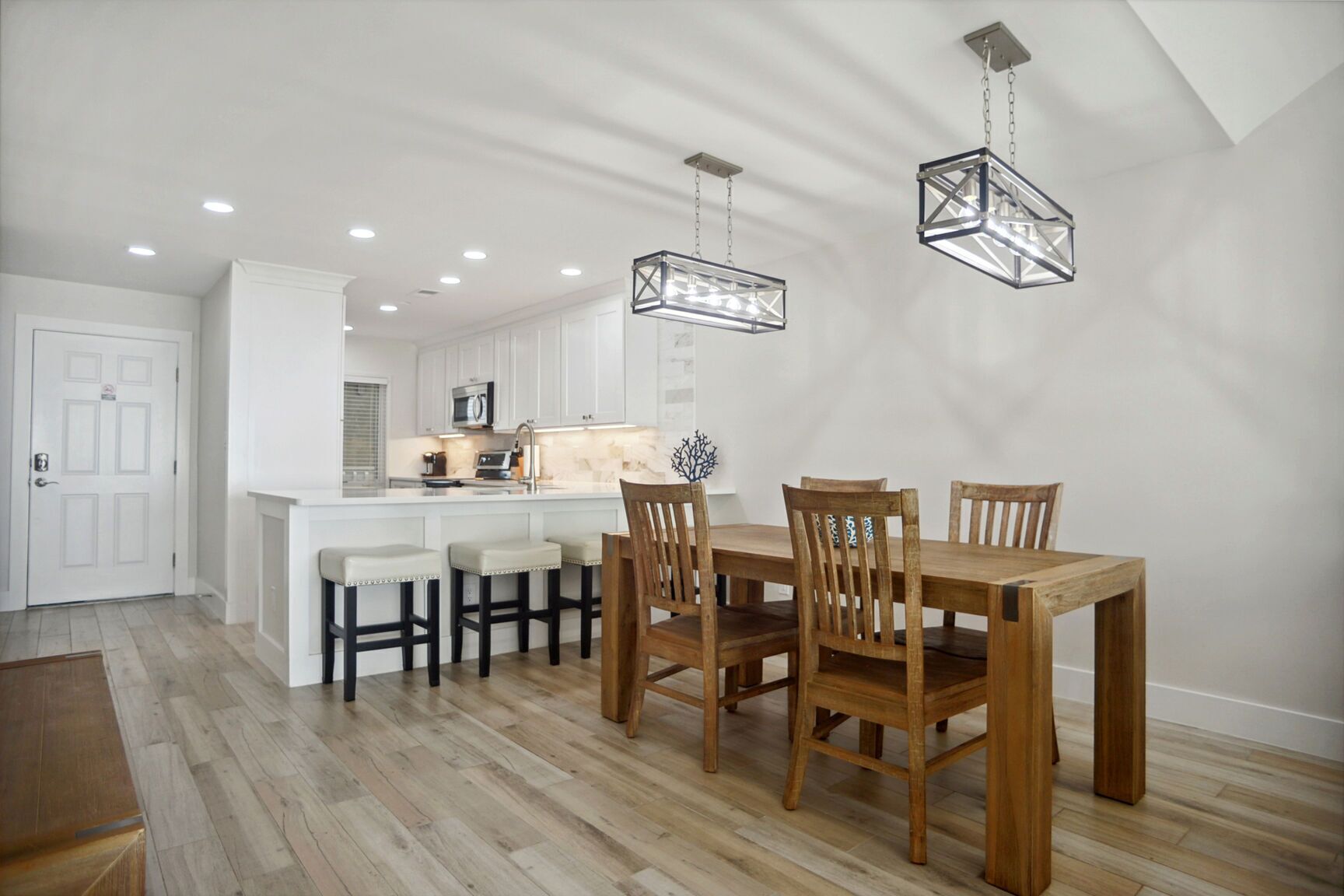A modern kitchen with white cabinetry, a central island, and pendant lighting.