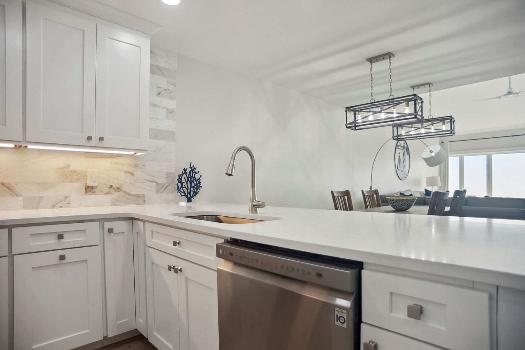 Una cocina moderna con armarios blancos, lavavajillas de acero inoxidable y una isla grande con un lavamanos.