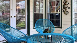 Eine überdachte Veranda mit blauen Stühlen, einem Deckenventilator und Wandbildern von Leguane.