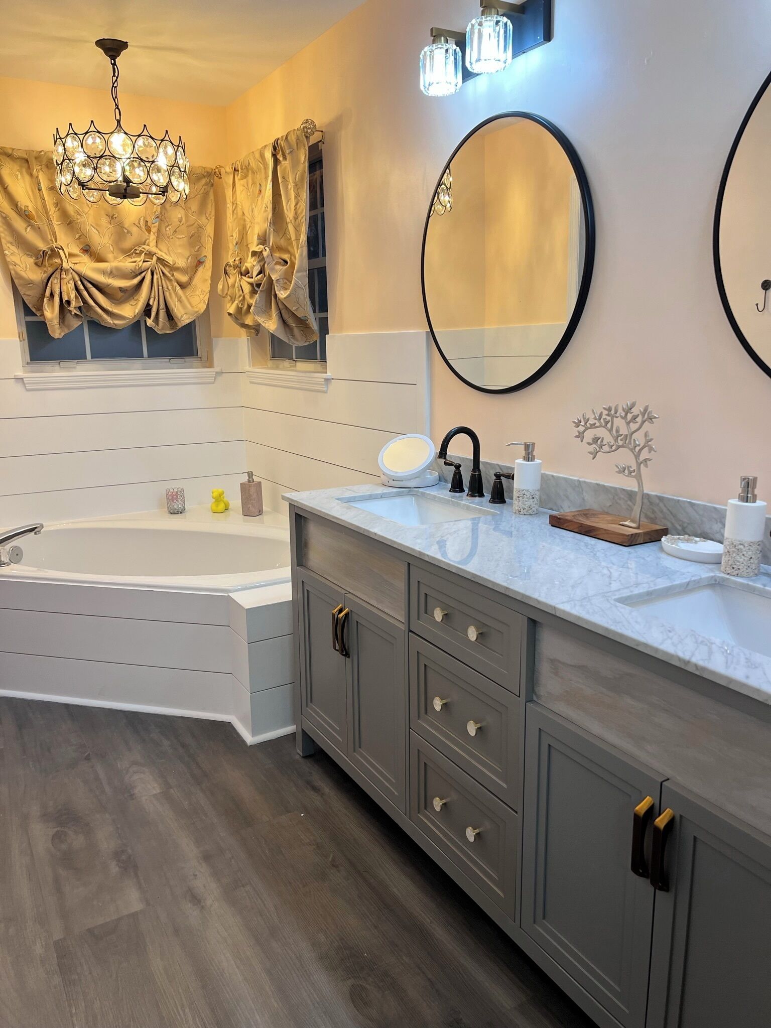 A modern bathroom with a freestanding bathtub, a vanity with a mirror, and a chandelier.