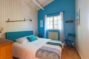 Un dormitorio con una cama, una ventana con cortinas, una silla, un radiador y una pared con un cartel.