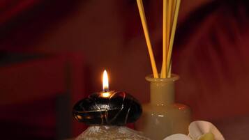 Uma vela, incensos, uma pedra e uma orquídea sobre uma mesa.