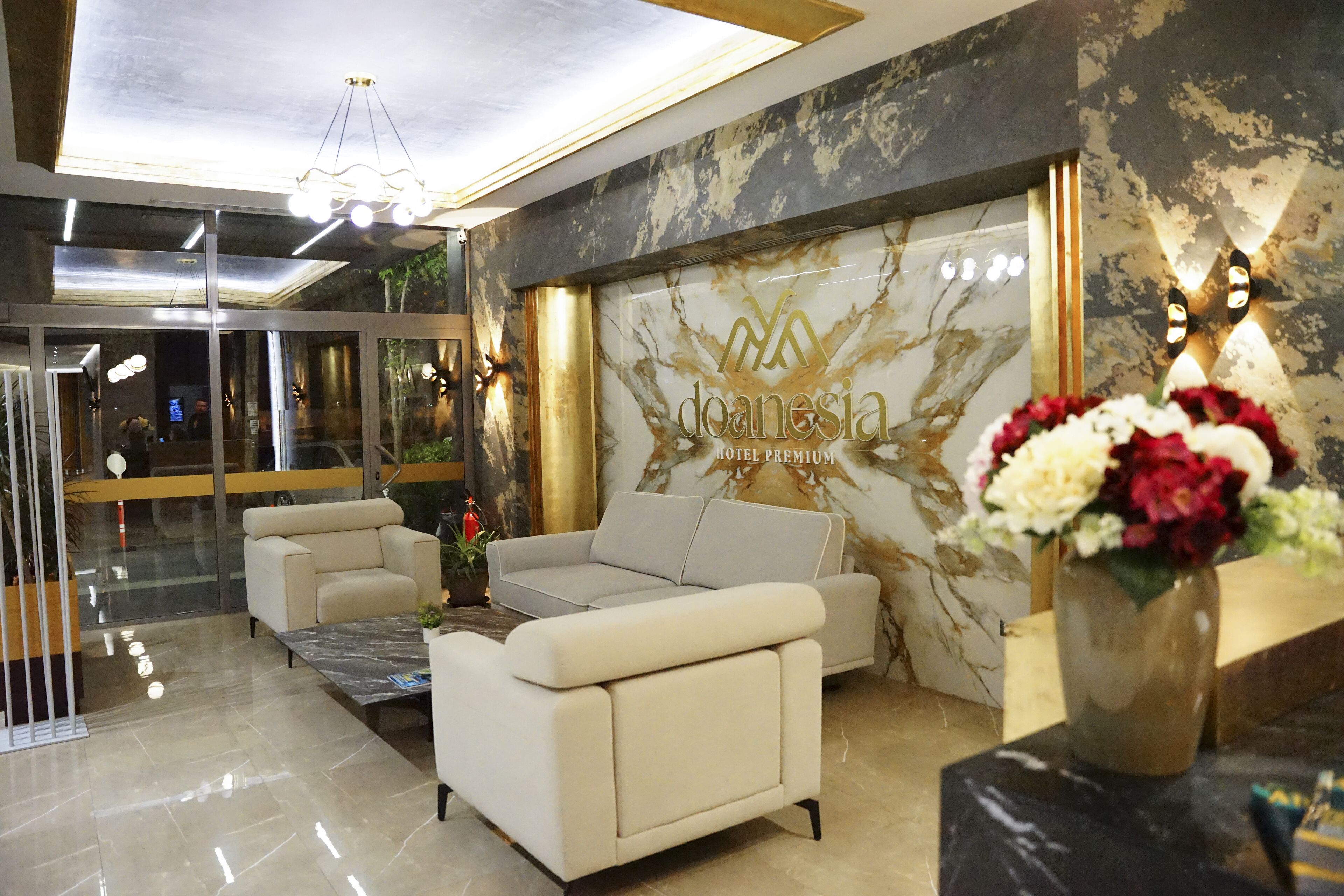 Eine Hotelhalle mit einer Rezeption, einer Couch und einem Blumenstrauß.