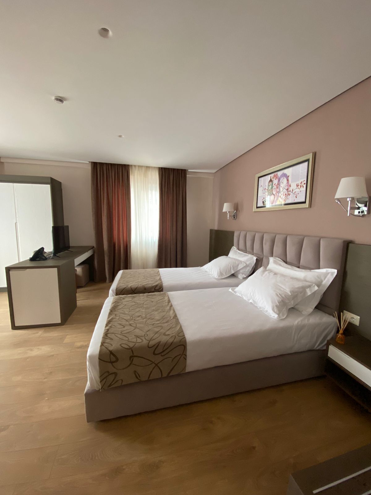 Une chambre d’hôtel avec un grand lit, un bureau, une armoire et un tableau au mur.