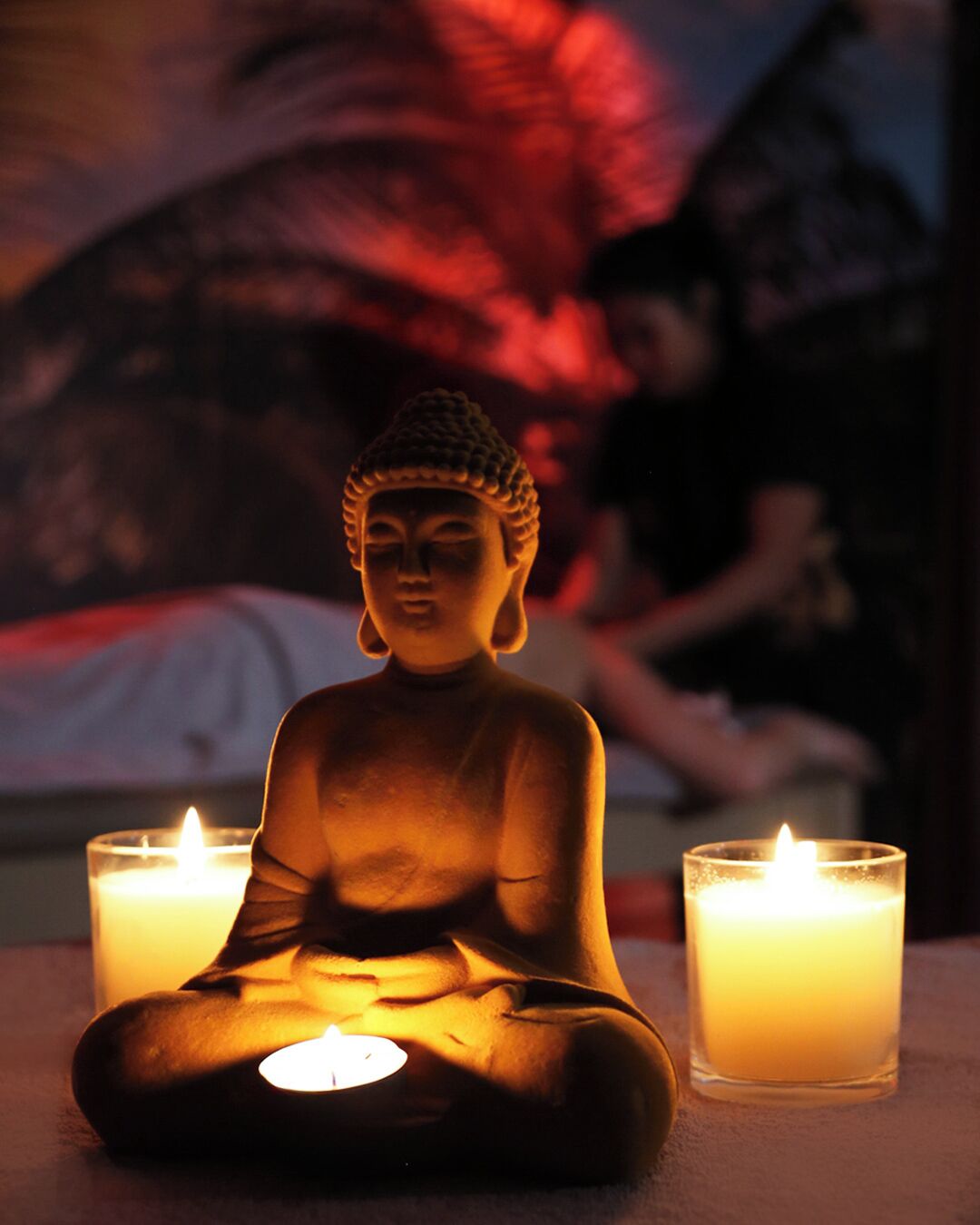 A Buddha statue with two lit candles in front.