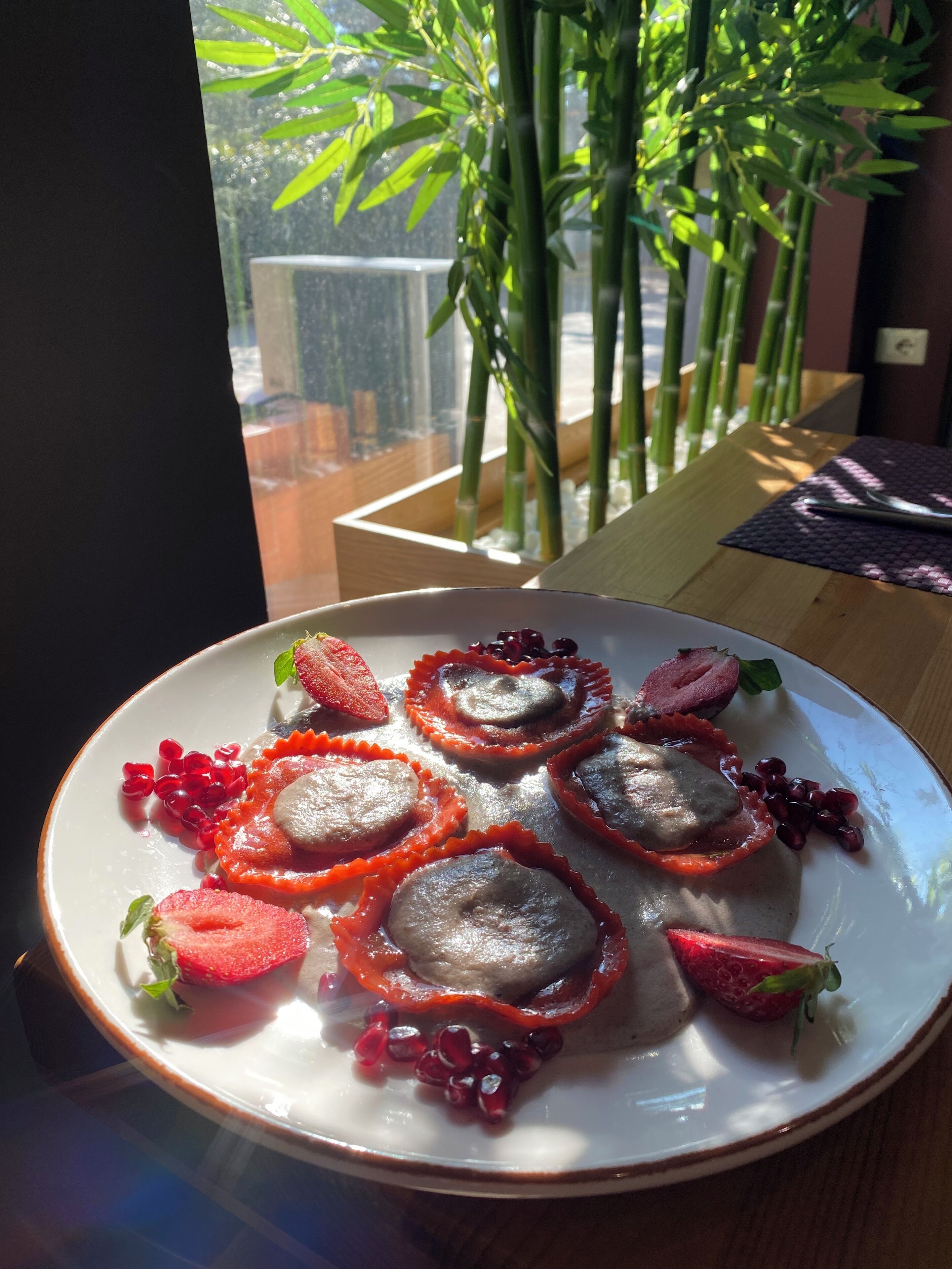 Un plato de comida con fresas y semillas de granada sobre un plato blanco.