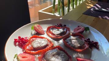Un plato de comida con fresas y semillas de granada sobre un plato blanco.