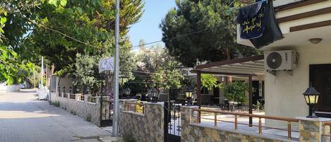 A paved street with a stone wall and a building with an air conditioning unit.
