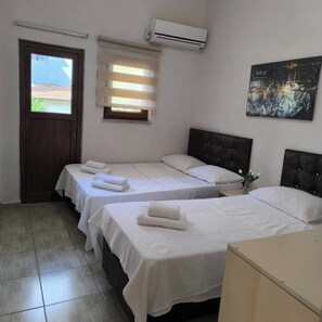 A hotel room with three beds, a door, an air conditioning unit, a window with blinds, and a painting on the wall. - Avşar Apart Motel (Marmara)