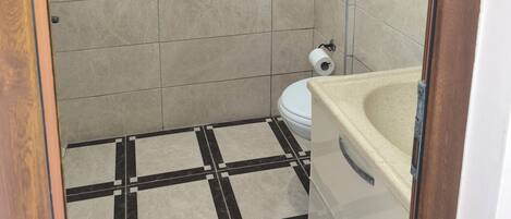 Un baño pequeño con inodoro, lavamanos y zona de ducha.