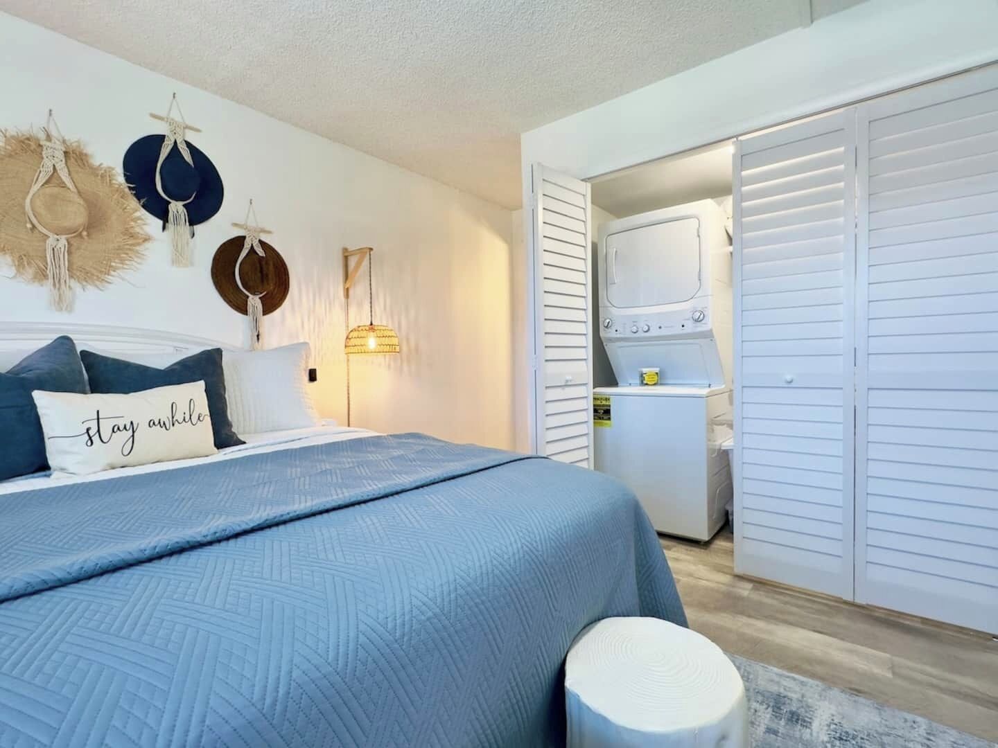 Une chambre à coucher comprenant un lit, une table de chevet, une lampe fixée au mur et une armoire.
