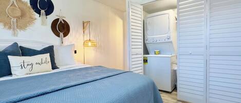 Une chambre à coucher comprenant un lit, une table de chevet, une lampe fixée au mur et une armoire.