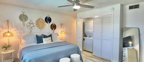 A bedroom with a bed, bedside lamps, a ceiling fan, a wardrobe, and a mirror.