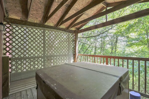 A covered outdoor area with a table, wooden beams, and a lattice fence.