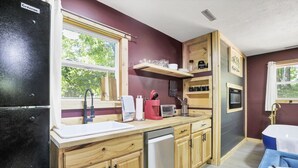 A compact kitchen with wooden cabinets, a built-in oven, and a window providing natural light. - Gentle Breeze: The Maple: Romantic Secluded Getaway (Lancaster)