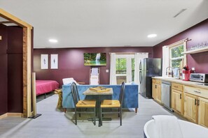 A compact kitchen with a dining area, a refrigerator, a microwave, and a sink.
