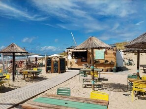 Relax by the beach at this charming café with outdoor seating and a paved walkway leading to the shore.