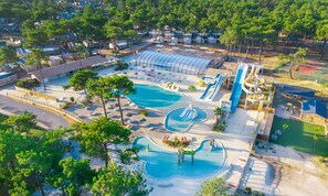 Relax in a serene outdoor oasis with multiple pools and water slides surrounded by lush greenery and shaded seating areas.