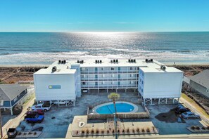 A hotel with a rooftop pool, a beach view, and a parking area with several cars. - Direct Oceanfront, Cherry Grove, Elevator, 2 Bedroom Condo (North Myrtle Beach)