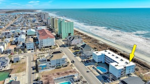 An aerial view of a coastal town with buildings along the beach, a road, and a body of water. - Direct Oceanfront, Cherry Grove, Elevator, 2 Bedroom Condo (North Myrtle Beach)